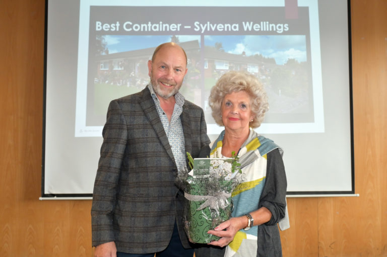 Commercial Manager Pete with winner Sylvena holding a rose, both in front of a screen which says 'Best Container'