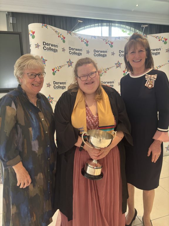 Overall Outstanding Student of 2024 Chloe Martin, dressed in black gown and gold sash, holding a silver cup, with chair of governors K Kimber and His Majesty's Lord-Lieutenant of Shropshire Anna Turner.