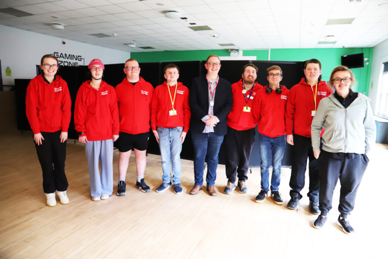 Eight members of the Student Council dressed in red Student Council hoodies stand in a line in the Student Union with councillor Craig Emery.